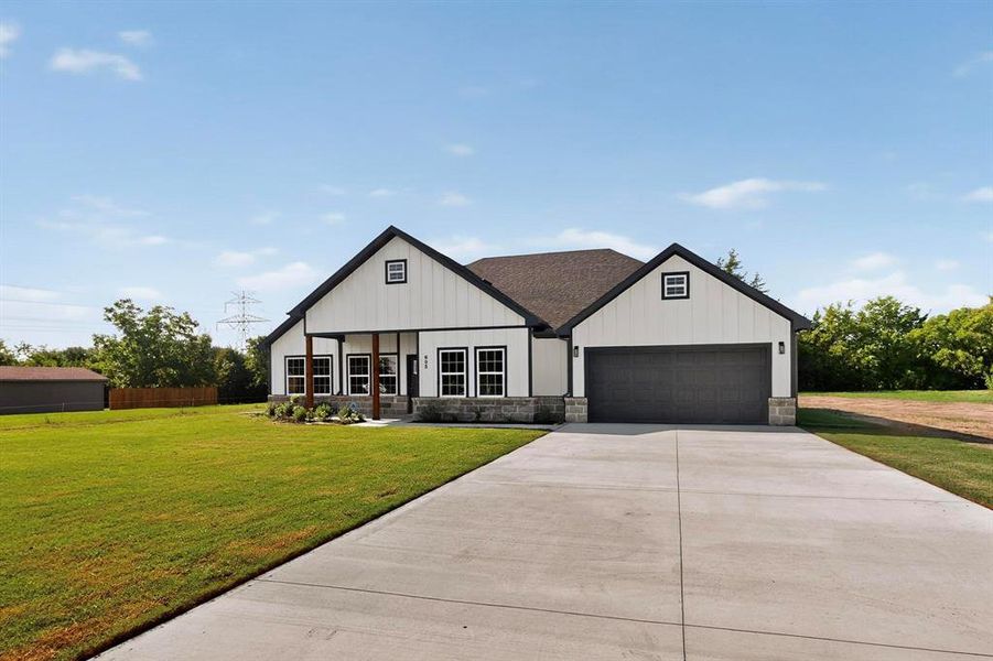 Modern farmhouse style home with board and batten siding, driveway, stone siding, and an attached garage Modern farmhouse style home with board and batten siding, driveway, stone siding, and an attached garage