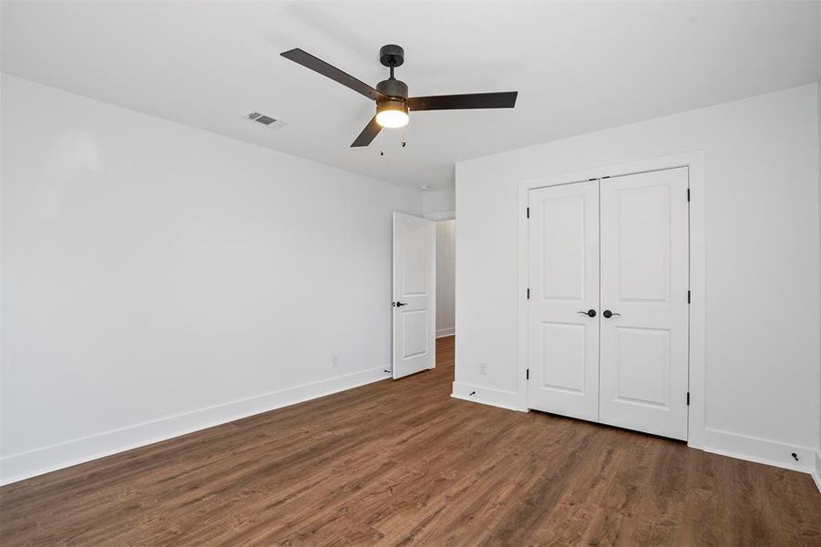 Unfurnished bedroom featuring baseboards, visible vents, ceiling fan, dark wood-type flooring, and a closet