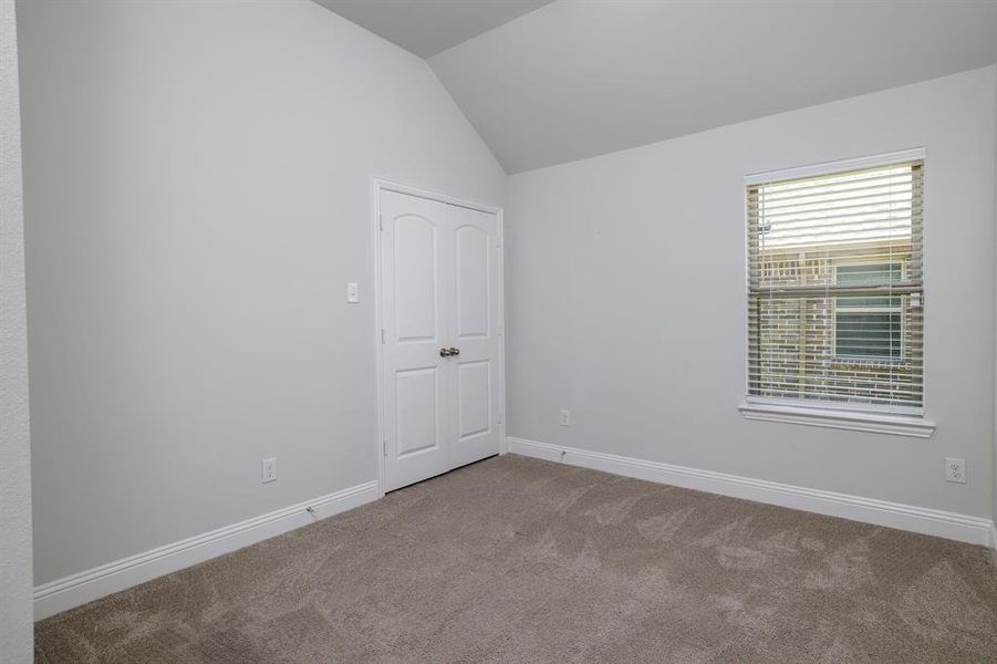 Unfurnished room with carpet and vaulted ceiling