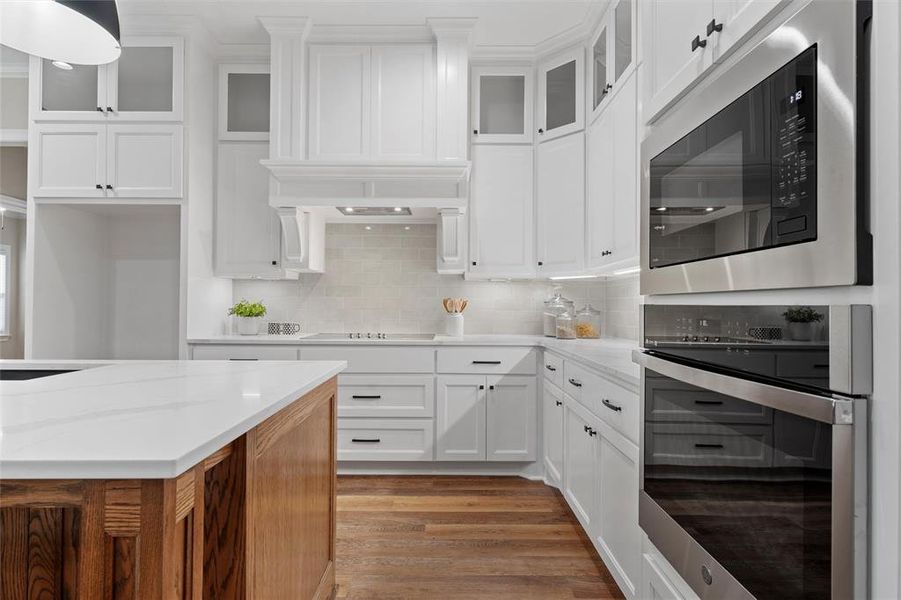 Kitchen with light wood-style flooring, built in microwave, white cabinets, and oven
