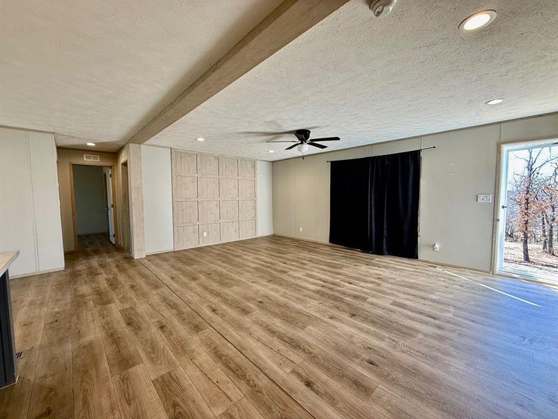 Unfurnished living room featuring a textured ceiling, light wood-style floors, recessed lighting, and ceiling fan Unfurnished living room featuring a textured ceiling, light wood-style floors, recessed lighting, and ceiling fan