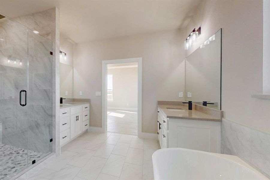 Full bathroom with a freestanding bath, two vanities, a marble finish shower, and a sink