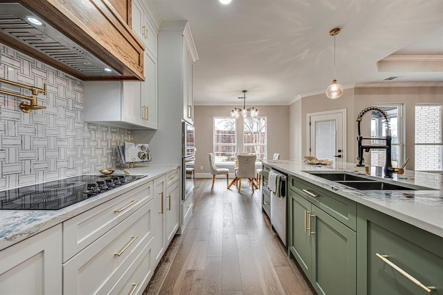 Kitchen with sink, white cabinets, custom range hood, and green cabinetry