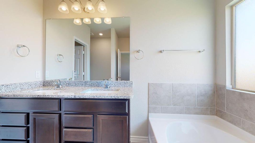 Bathroom featuring a double vanity with dark wood cabinetry, a granite countertop, and dual undermount sinks