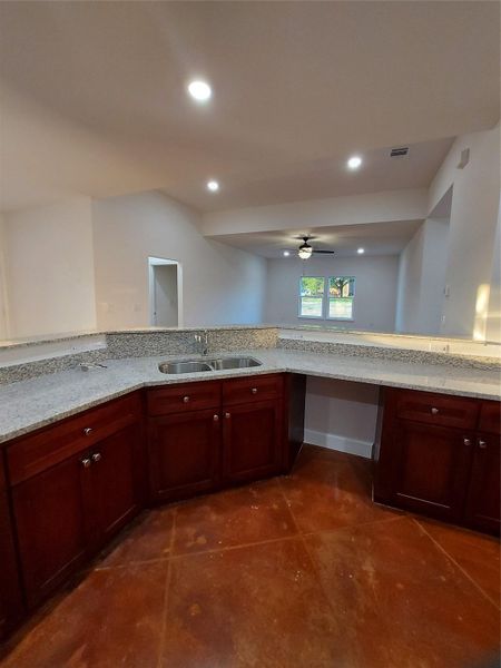Kitchen featuring light stone counters, a ceiling fan, recessed lighting, and bold wood finish cabinets