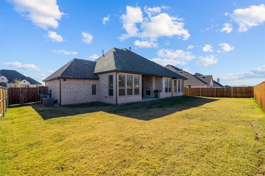 Rear view of property featuring a lawn and central AC