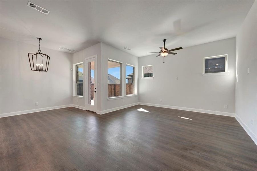 Unfurnished room featuring suspended lighting, dark wood-type flooring, and ceiling fan