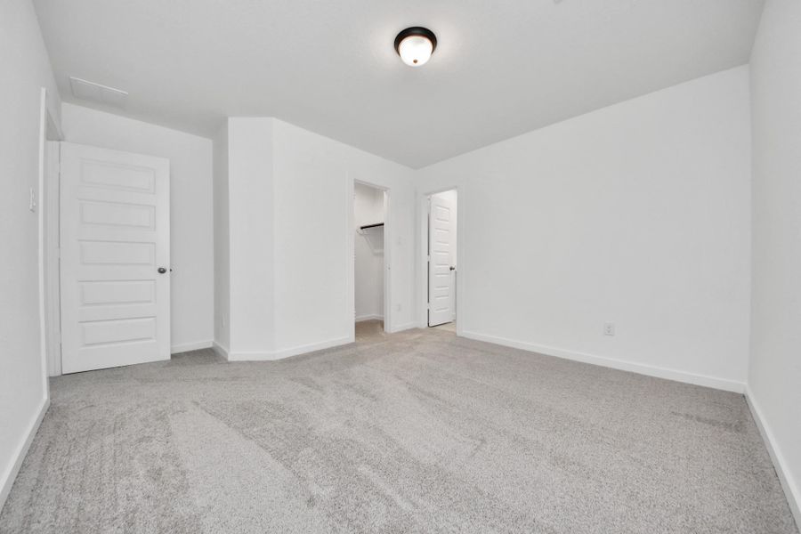 Secondary bedroom features plush carpeting, large windows that let in plenty of natural light, bright paint, and spacious closets.