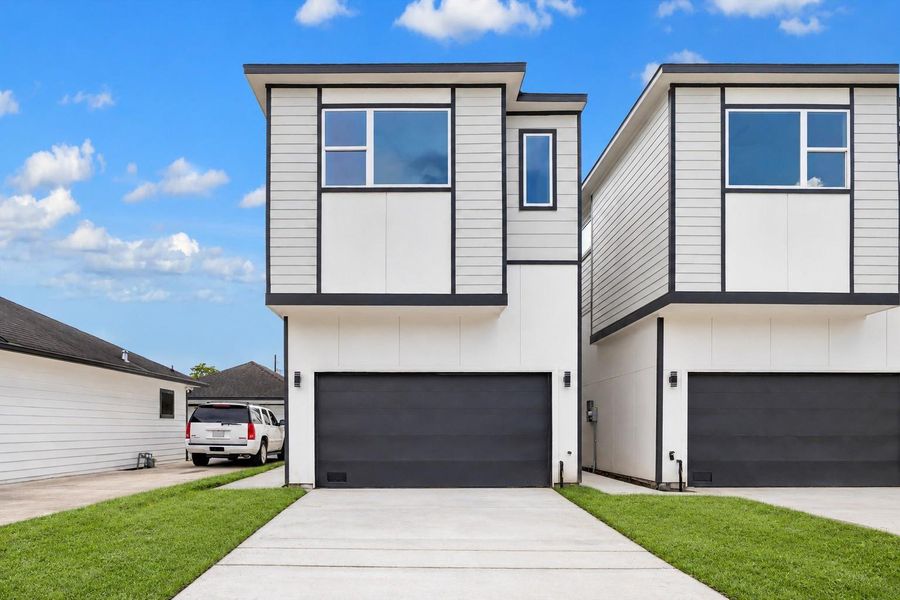 Striking contemporary architecture sets the tone with crisp white siding, bold black trim, oversized windows, and a sleek two-car garage door. Clean lines and a modern profile create standout curb appeal, while the tall front elevation gives the home a fresh, urban feel. A wide driveway provides convenient access, and the contrasting finishes add architectural interest from every angle. This photo has been digitally decluttered for visual reference. Striking contemporary architecture sets the tone with crisp white siding, bold black trim, oversized windows, and a sleek two-car garage door. Clean lines and a modern profile create standout curb appeal, while the tall front elevation gives the home a fresh, urban feel. A wide driveway provides convenient access, and the contrasting finishes add architectural interest from every angle. This photo has been digitally decluttered for visual reference.