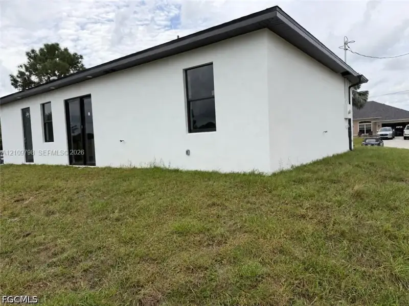Stucco exterior featuring dark-framed windows, a sliding glass door, and a low-pitch roofline