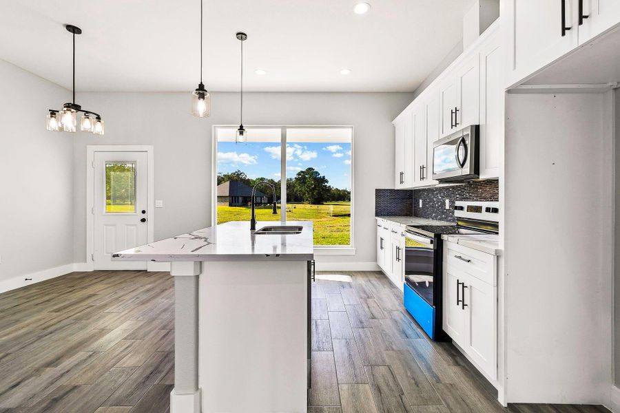 This modern kitchen features sleek white cabinetry, stainless steel appliances, and a central island with a chic marble countertop. Large windows offer abundant natural light and a view of the spacious backyard. The open layout and stylish lighting fixtures create an inviting and functional space. This modern kitchen features sleek white cabinetry, stainless steel appliances, and a central island with a chic marble countertop. Large windows offer abundant natural light and a view of the spacious backyard. The open layout and stylish lighting fixtures create an inviting and functional space.