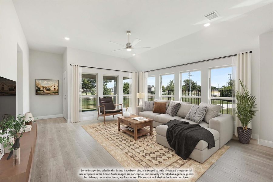 Living room with vaulted ceiling, large sectional sofa, hardwood floors, and multiple windows with backyard views