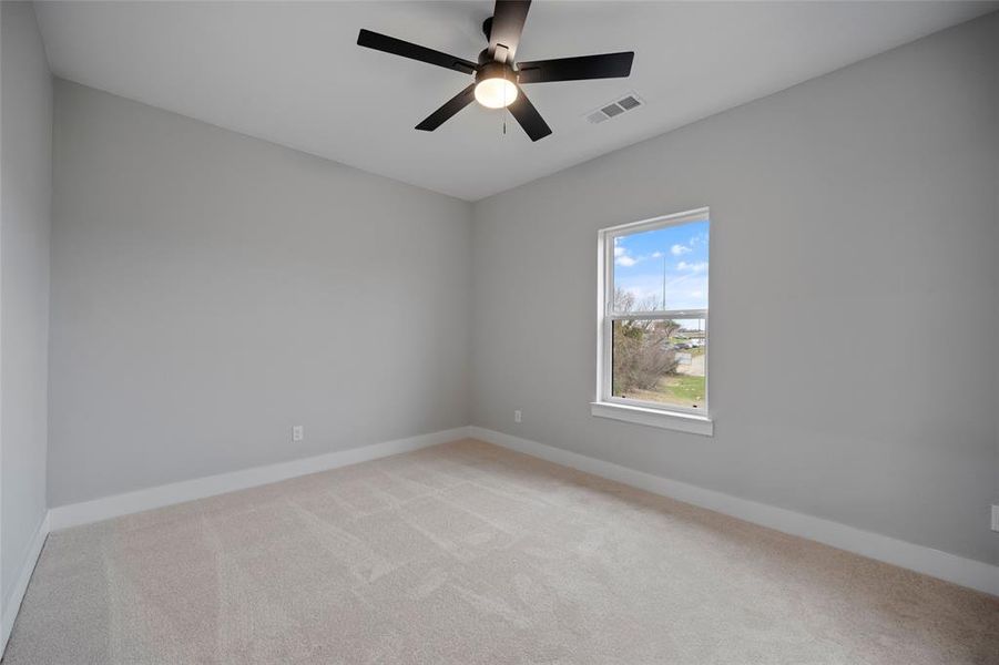 Spare room with visible vents, light colored carpet, a ceiling fan, and baseboards