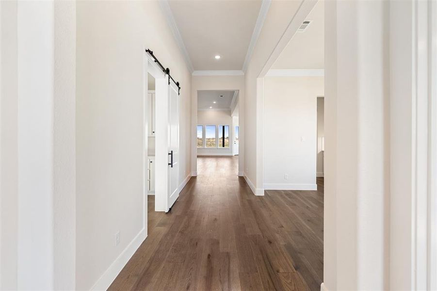 Hallway featuring a barn door, dark wood finished floors, crown molding, and recessed lighting