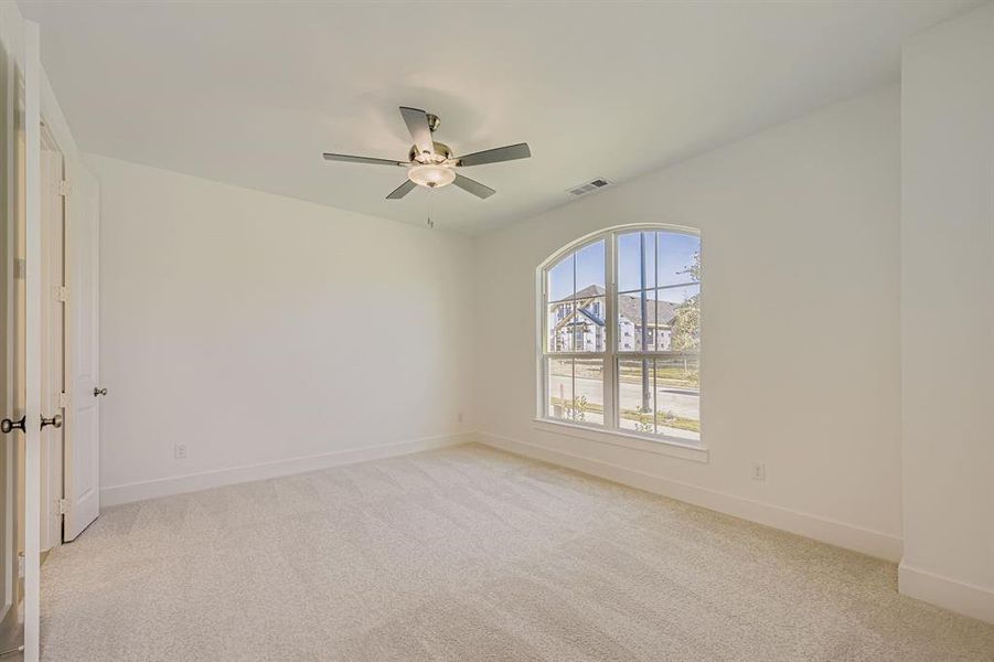 Unfurnished room featuring light carpet and a ceiling fan