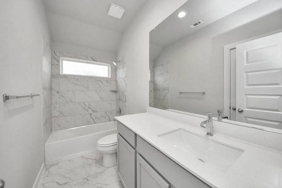 Secondary bath features tile flooring, bath/shower combo with tile surround, light stained wood cabinets, beautiful light countertop. Sample photo of completed home with similar floor plan. Actual colors and selections may vary. Secondary bath features tile flooring, bath/shower combo with tile surround, light stained wood cabinets, beautiful light countertop. Sample photo of completed home with similar floor plan. Actual colors and selections may vary.