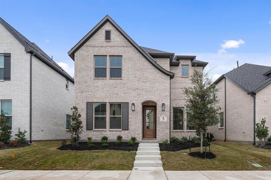 French country home featuring a front yard and brick siding