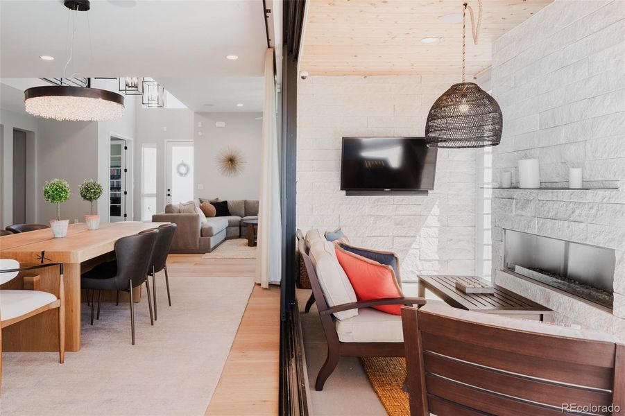 Walls disappear to expose the lanai where a modern stone fireplace, timber ceiling and designer lighting elevate your after dinner conversations.