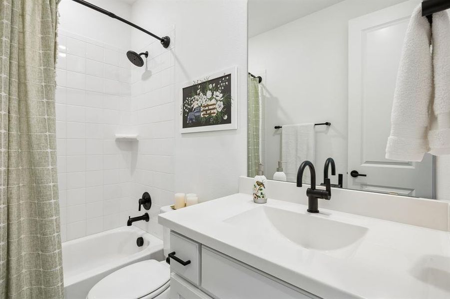 Bathroom featuring a single vanity with an integrated sink, matte black hardware, and a tub-shower combination with subway tile surround Bathroom featuring a single vanity with an integrated sink, matte black hardware, and a tub-shower combination with subway tile surround