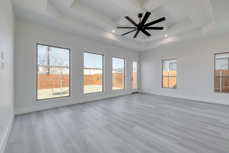 Unfurnished room with baseboards, a ceiling fan, a tray ceiling, and wood finished floors