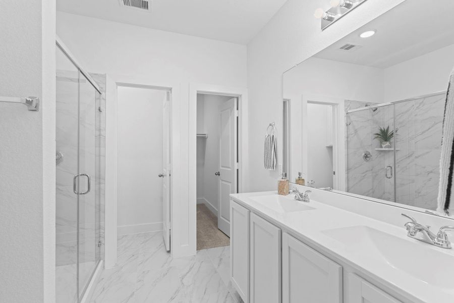 The primary bathroom features a long his and her private sinks vanity, bright lighting, and beautiful finishes that make your morning routine feel effortless and relaxing. Beautiful tile floors bring a bright and polished finish to the bathroom.