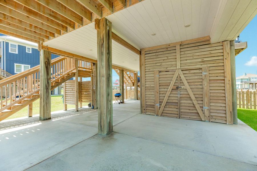 Expansive covered parking area includes a large enclosed storage room, offering plenty of space for beach gear, tools, and outdoor equipment.