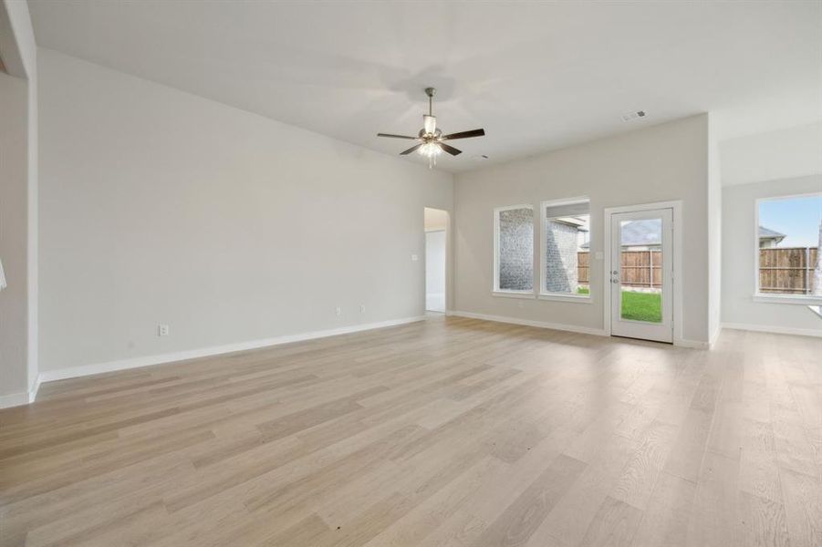 The living room features a ceiling fan and windows to the backyard