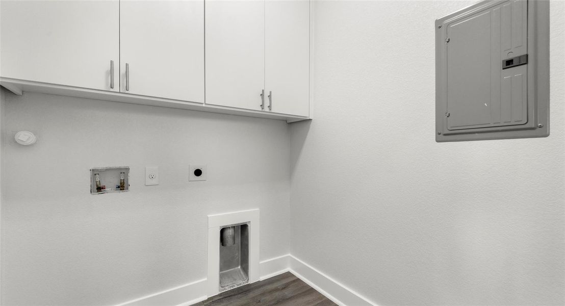 Washroom with electric panel, dark wood finished floors, hookup for a washing machine, hookup for an electric dryer, and cabinet space