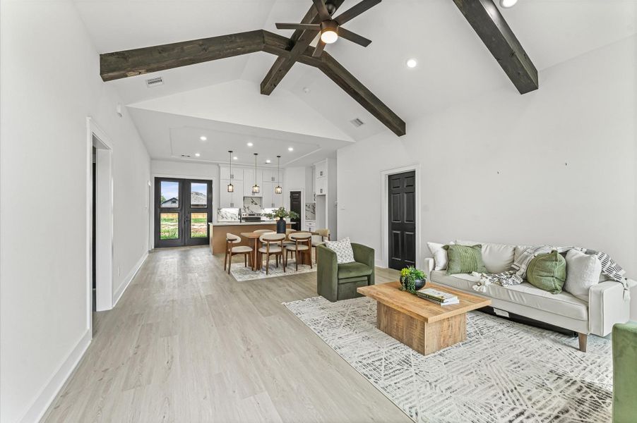 Bright and open living area with soaring cathedral ceilings and warm wood accents. High cathedral ceilings in living room. Photos are representative of the same floor plan built by this builder. Finishes will be the same or similar.