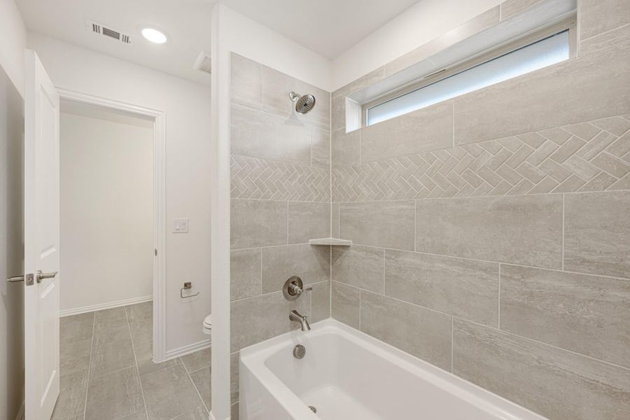 Bathroom with soaking tub, tiled shower surround featuring herringbone accent, and separate toilet room Bathroom with soaking tub, tiled shower surround featuring herringbone accent, and separate toilet room