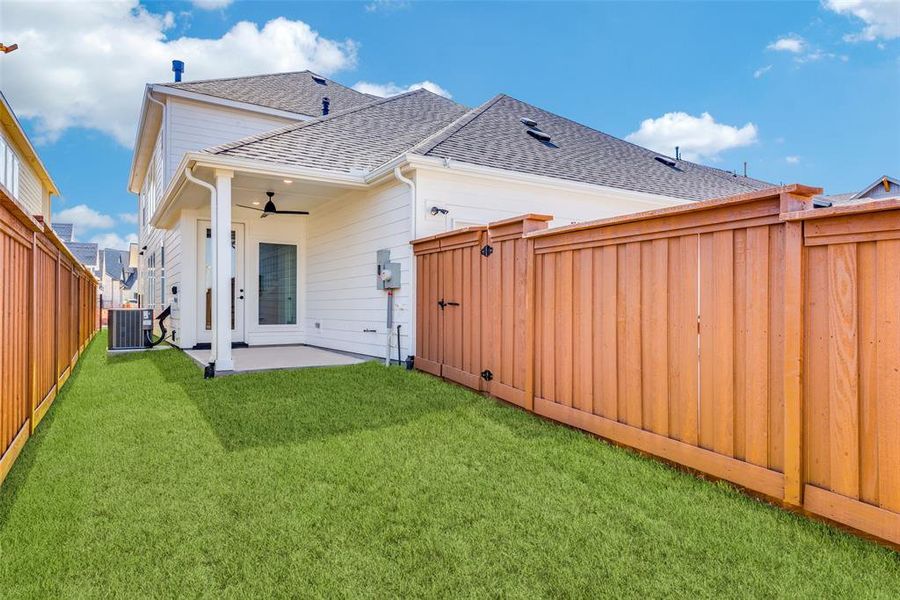 Rear view of property featuring a yard, ceiling fan, cooling unit, and a patio area