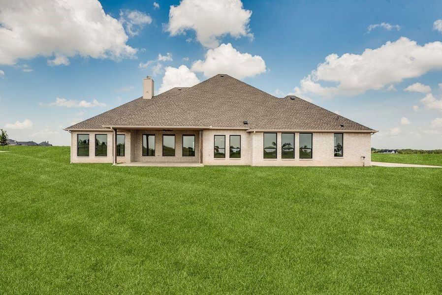 Back of house with a lawn, roof with shingles, a patio area, a chimney, and brick siding