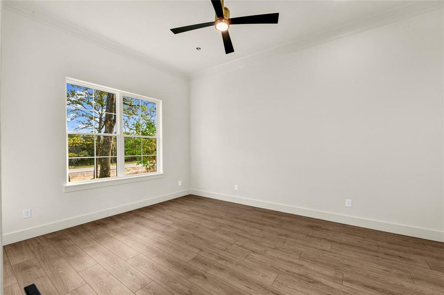 Unfurnished room with ornamental molding, wood finished floors, and a ceiling fan Unfurnished room with ornamental molding, wood finished floors, and a ceiling fan
