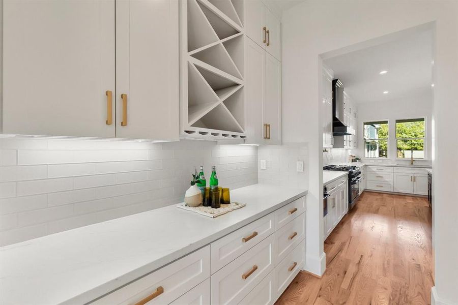 Stylish butler’s pantry with custom cabinetry, undercabinet lighting, built-in wine storage, and seamless access to the kitchen.