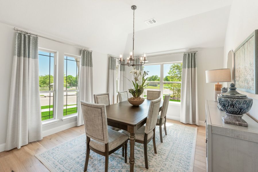 Dining room with dark wood table, six upholstered chairs, chandelier, and large windows with natural light