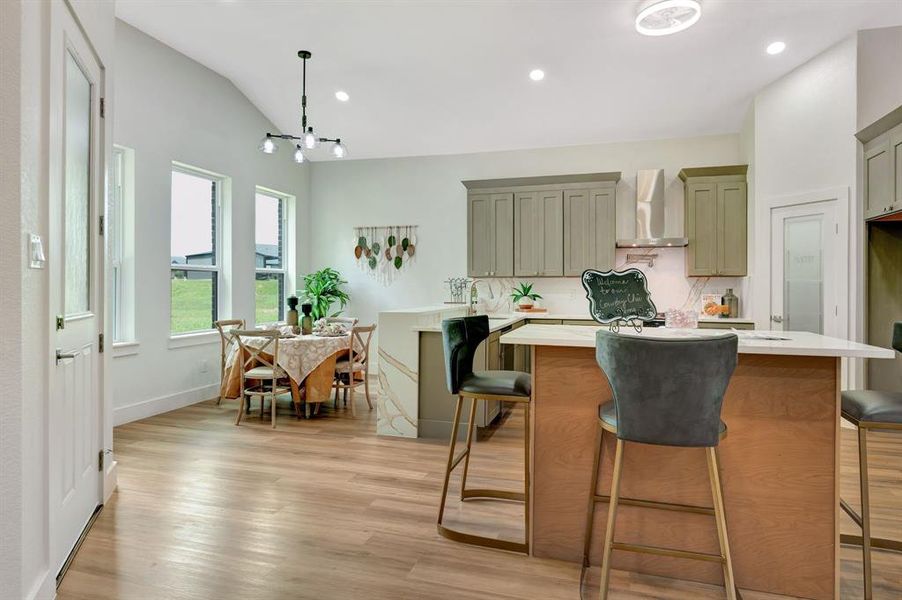 Open-concept kitchen and dining area featuring wood-finish flooring, vaulted ceilings, and recessed lighting Open-concept kitchen and dining area featuring wood-finish flooring, vaulted ceilings, and recessed lighting
