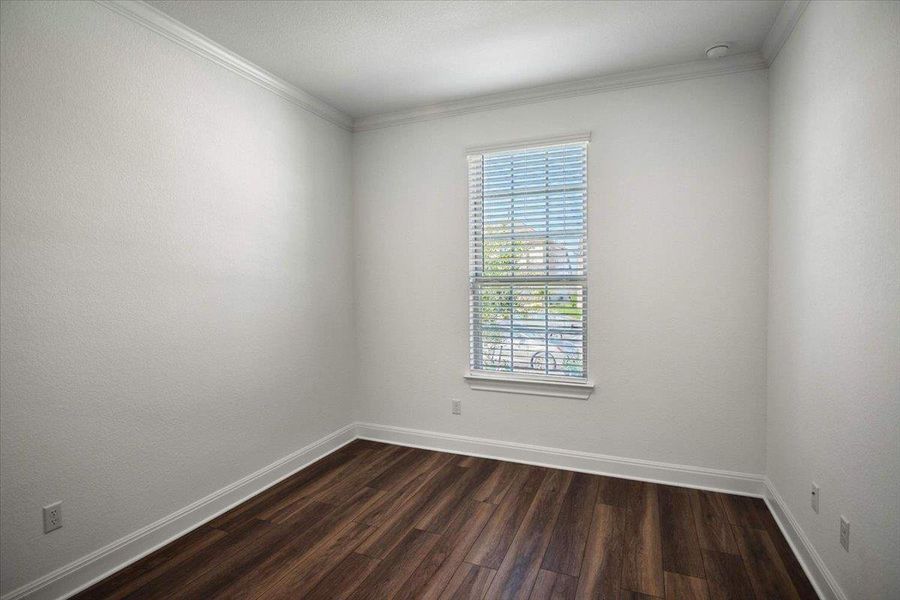 Rich wood flooring grounds this naturally illuminated room, complemented by crisp white trim.