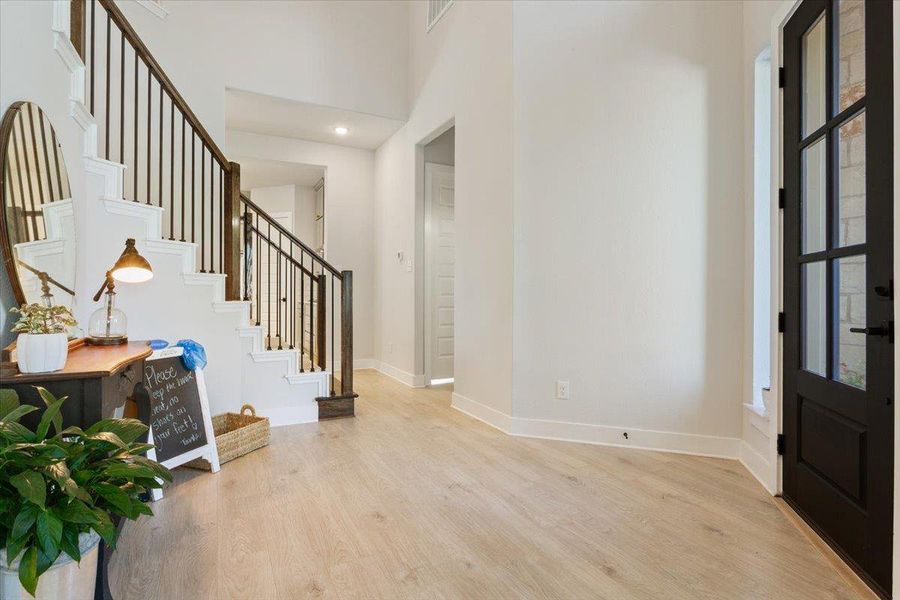 Entryway featuring light wood-type flooring, a high ceiling, and recessed lighting