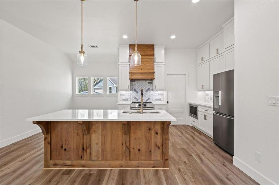 Kitchen featuring decorative backsplash, light wood finished floors, light countertops, stainless steel appliances, and recessed lighting Kitchen featuring decorative backsplash, light wood finished floors, light countertops, stainless steel appliances, and recessed lighting