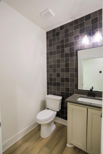 Half bath featuring tile walls, vanity, and light wood-style flooring