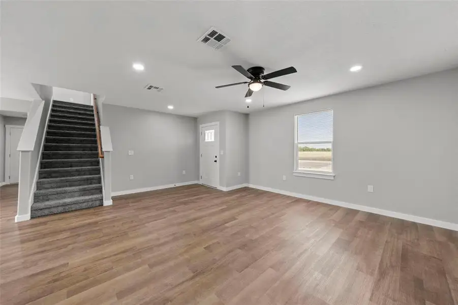 Unfurnished living room featuring stairs, a ceiling fan, light wood finished floors, and recessed lighting Unfurnished living room featuring stairs, a ceiling fan, light wood finished floors, and recessed lighting
