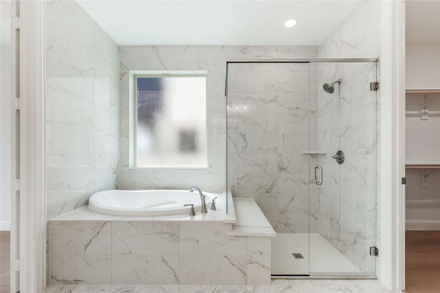 Bathroom with marble tile walls, soaking tub, and glass-enclosed walk-in shower