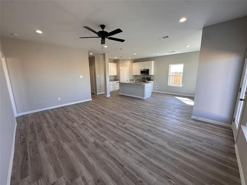 Unfurnished living room featuring ceiling fan and hardwood / wood-style floors