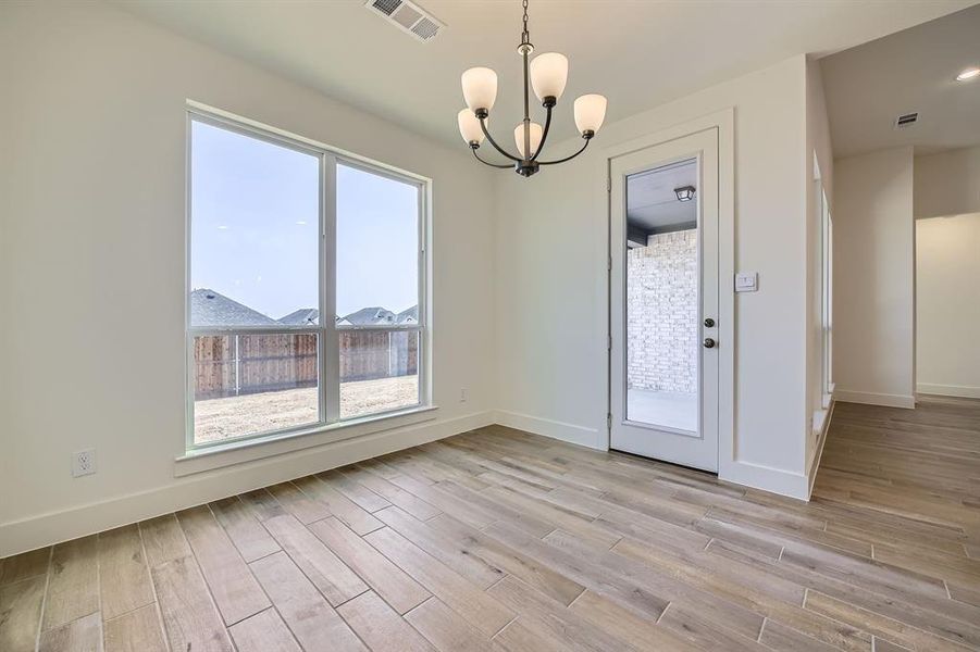 Empty room featuring visible vents, baseboards, light wood-style floors, and a chandelier