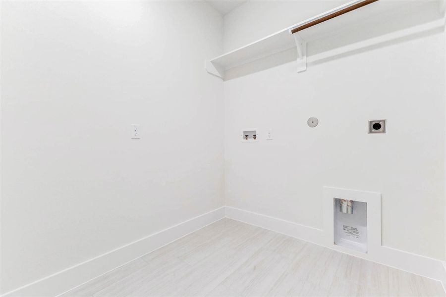 Laundry room area with space for an additional refrigerator or custom cabinetry. Durable tile flooring and full baseboards — even in utility areas — reflect the home’s attention to detail.