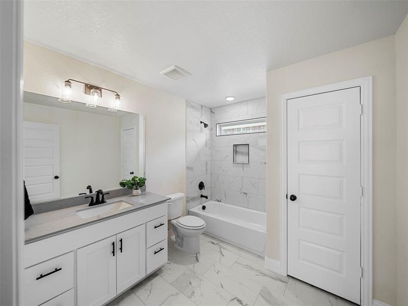 Full bathroom with toilet, vanity, and tiled shower / bath