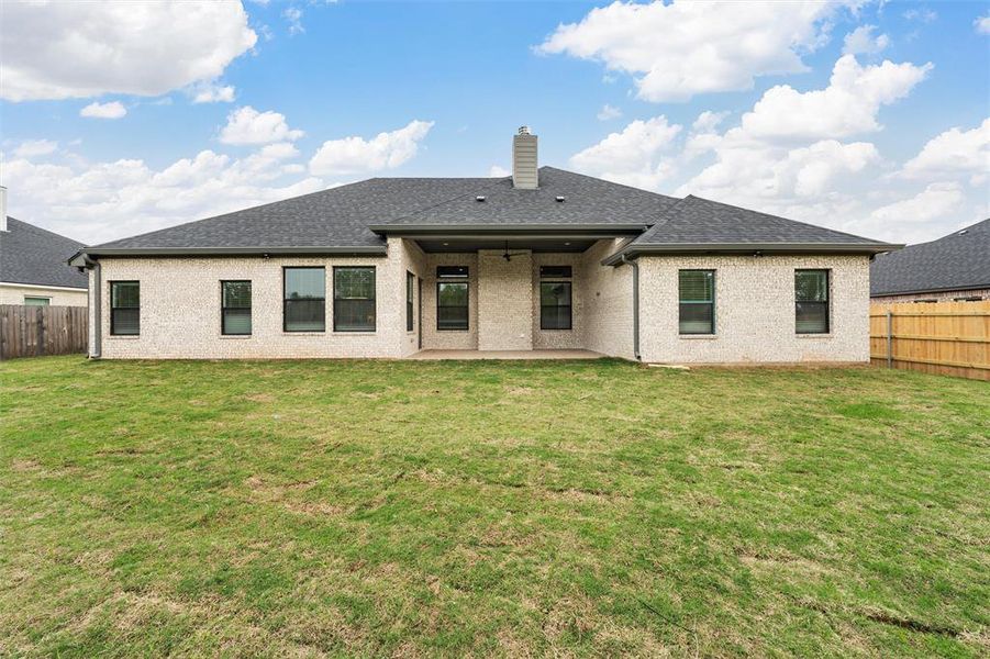 Rear view of house featuring a fenced backyard, a patio, a chimney, and a lawn
