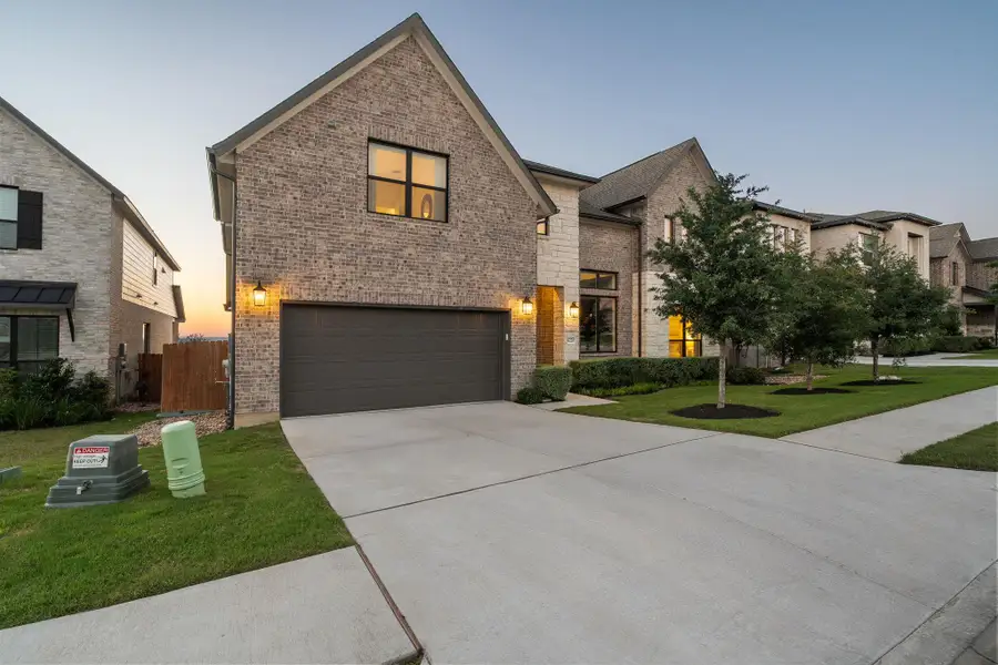 Contemporary brick and stone exterior with a two-car garage, concrete driveway, and established landscaping Contemporary brick and stone exterior with a two-car garage, concrete driveway, and established landscaping