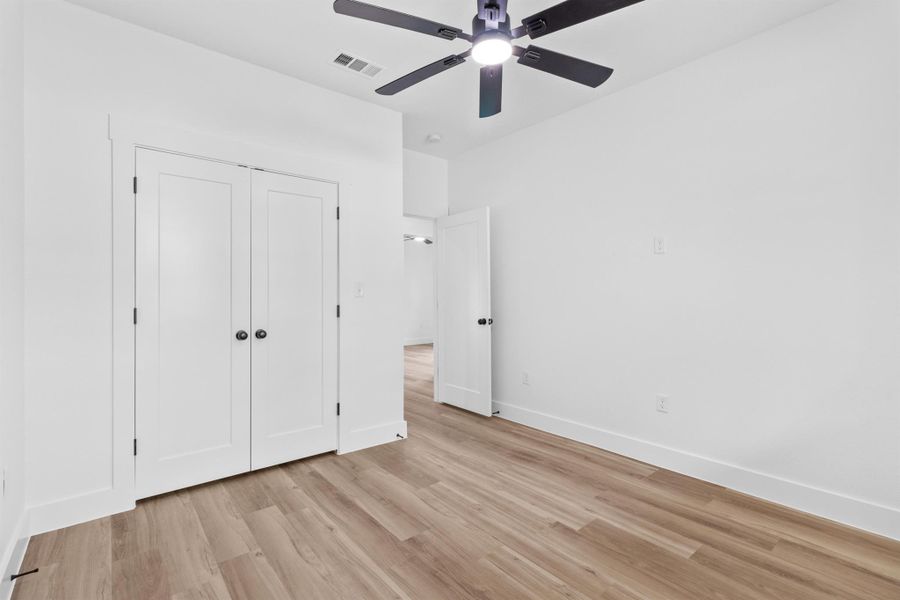 Unfurnished bedroom featuring light wood finished floors, a ceiling fan, and a closet
