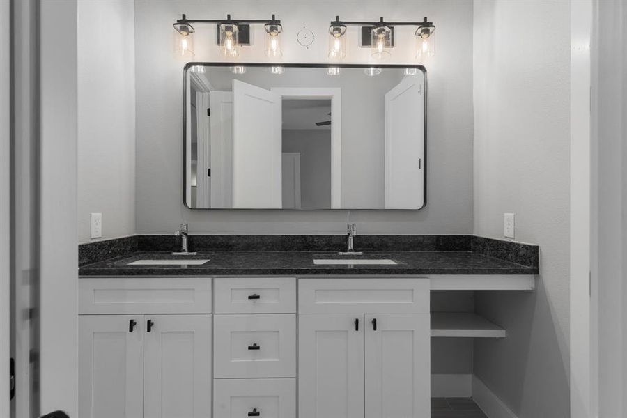 Bathroom featuring a sink, baseboards, and double vanity